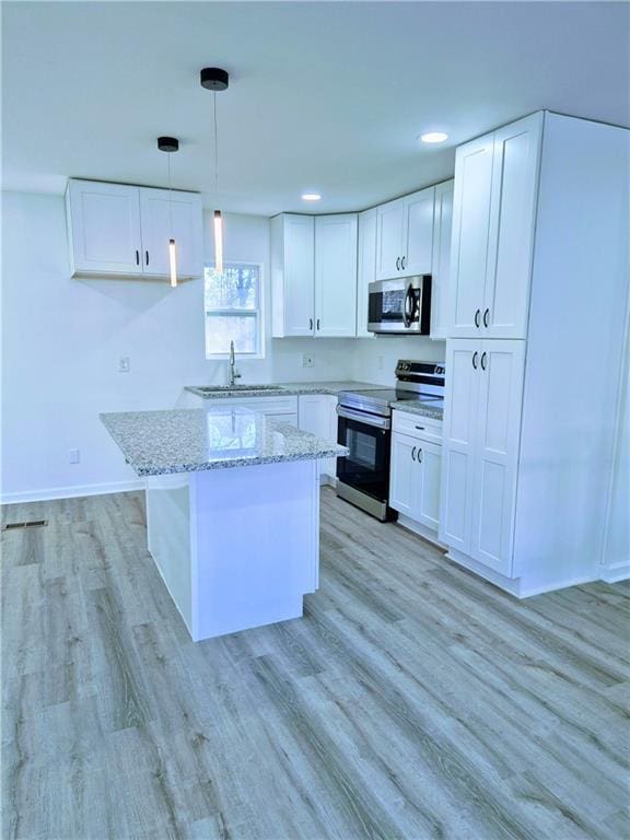 kitchen featuring appliances with stainless steel finishes, light stone countertops, a kitchen island, and white cabinets