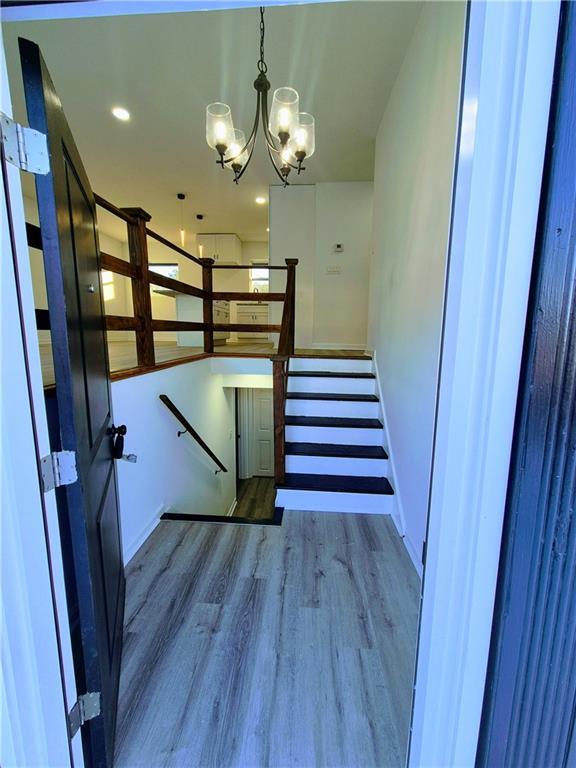 stairs with hardwood / wood-style flooring and an inviting chandelier