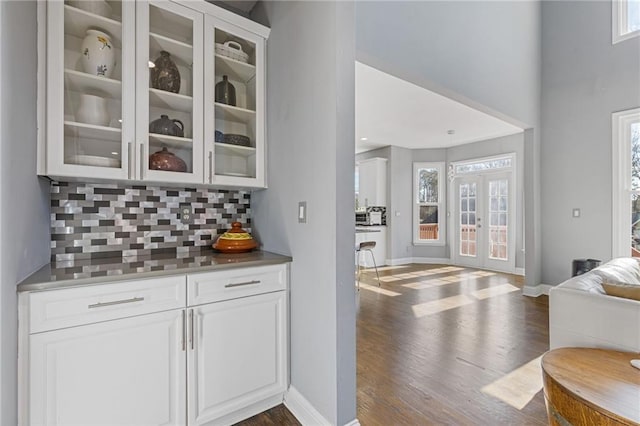 bar featuring french doors, dark hardwood / wood-style floors, decorative backsplash, and white cabinets