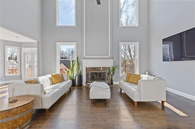 living room with dark wood-type flooring, a towering ceiling, and a premium fireplace