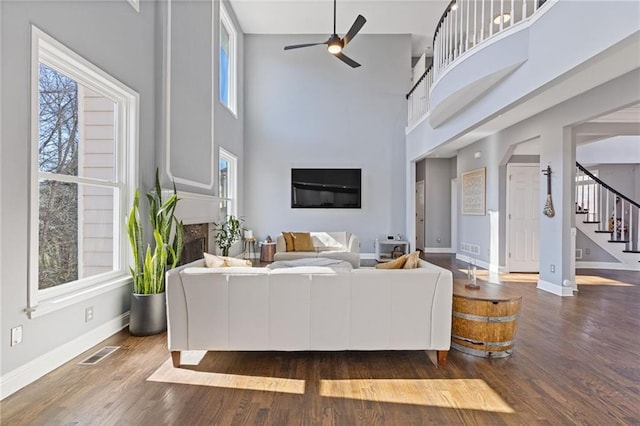 living room featuring ceiling fan, dark hardwood / wood-style floors, and a high ceiling