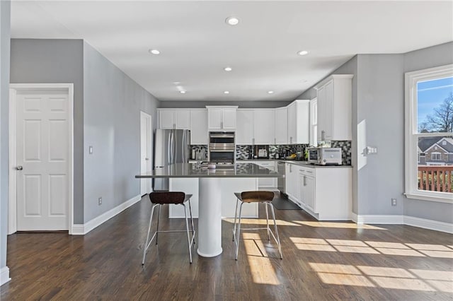 kitchen featuring white cabinetry, appliances with stainless steel finishes, a center island, and a kitchen bar