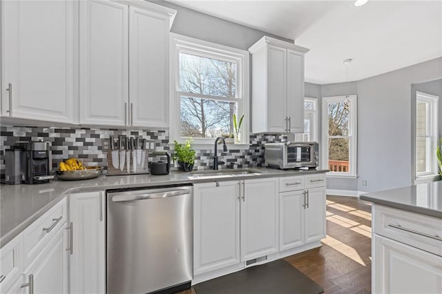 kitchen featuring sink, stainless steel dishwasher, dark hardwood / wood-style floors, decorative backsplash, and white cabinets