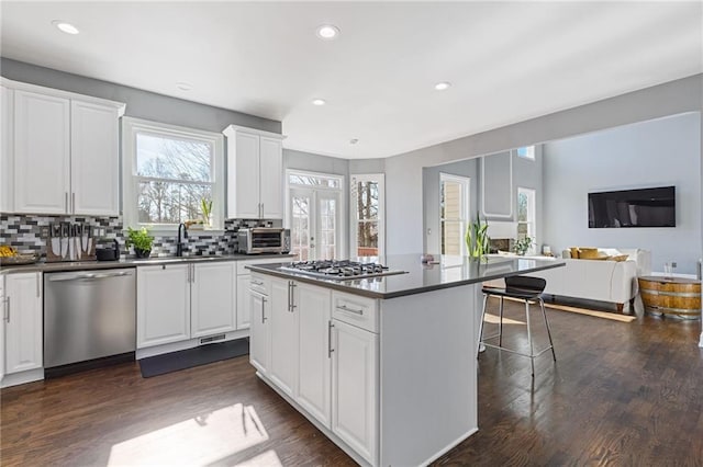 kitchen featuring white cabinetry, a kitchen bar, a center island, and appliances with stainless steel finishes