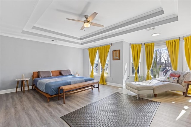 bedroom featuring ornamental molding, light wood-type flooring, and a tray ceiling