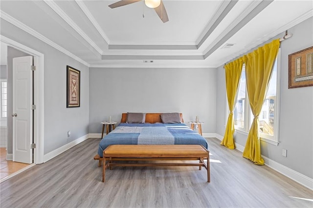 bedroom with ornamental molding, a raised ceiling, ceiling fan, and light wood-type flooring