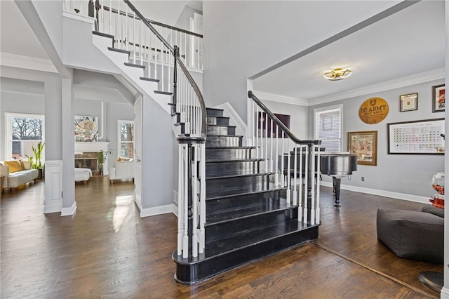 stairs with ornamental molding, hardwood / wood-style floors, and a high ceiling