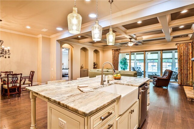 kitchen featuring a kitchen island with sink, coffered ceiling, ceiling fan with notable chandelier, hanging light fixtures, and beamed ceiling