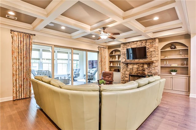 living room with hardwood / wood-style flooring, built in shelves, ceiling fan, and a fireplace