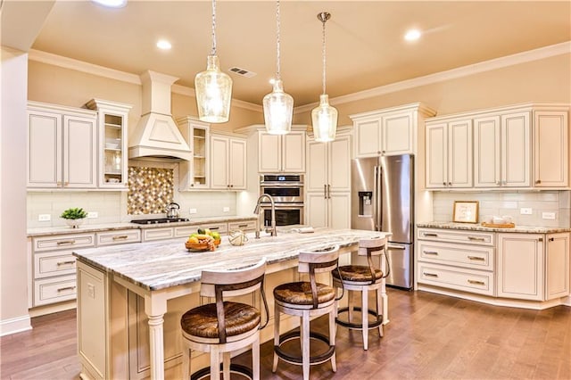 kitchen with a kitchen breakfast bar, light stone counters, pendant lighting, a center island with sink, and appliances with stainless steel finishes