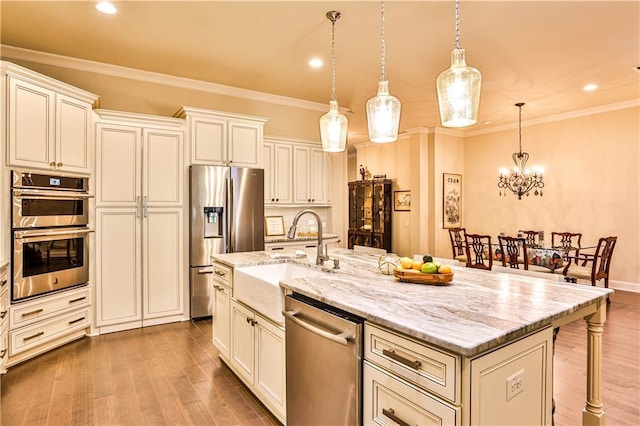 kitchen featuring hanging light fixtures, appliances with stainless steel finishes, a kitchen island with sink, and a breakfast bar area