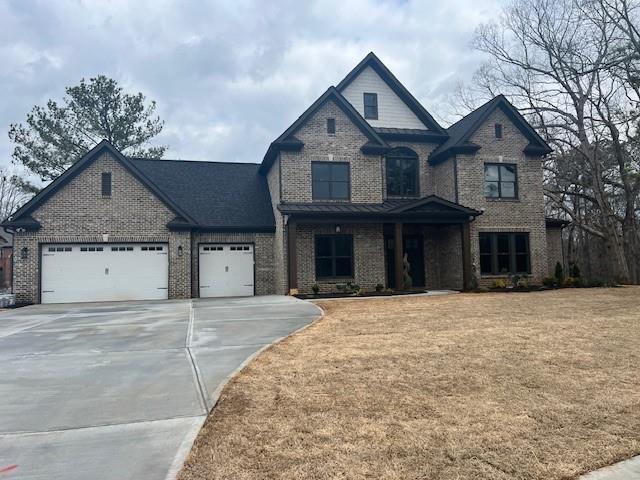 view of front facade with driveway, brick siding, an attached garage, and a front yard