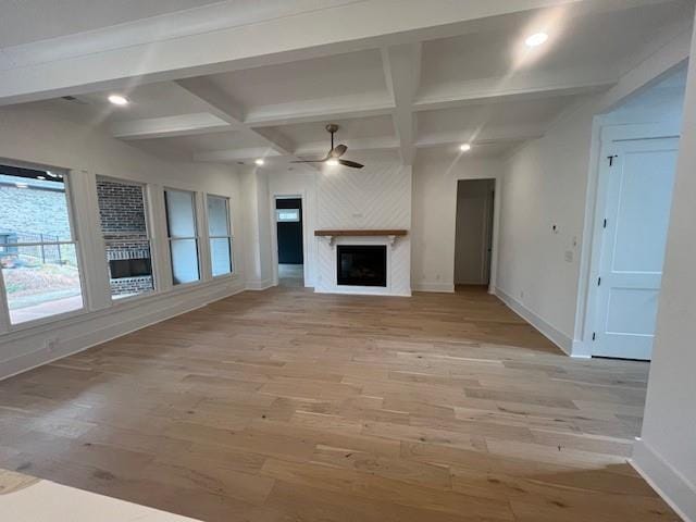 unfurnished living room with baseboards, ceiling fan, a fireplace, and light wood-style floors