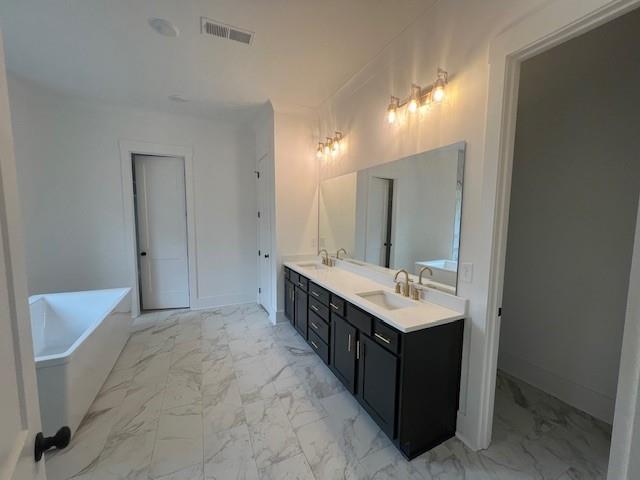 bathroom with marble finish floor, visible vents, a sink, and a soaking tub