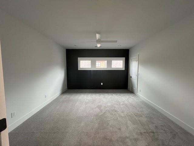 carpeted empty room featuring a ceiling fan and baseboards