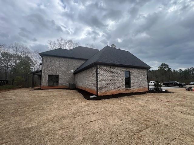 view of side of property featuring cooling unit and brick siding