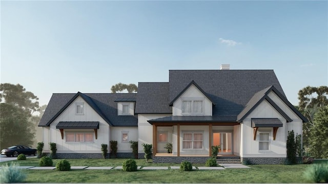 modern farmhouse with metal roof, a front yard, a standing seam roof, board and batten siding, and roof with shingles