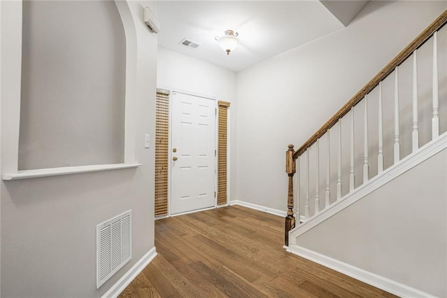 foyer entrance with baseboards, stairs, visible vents, and wood finished floors