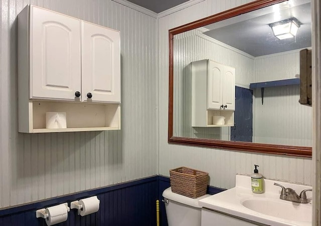 bathroom with toilet, vanity, and ornamental molding