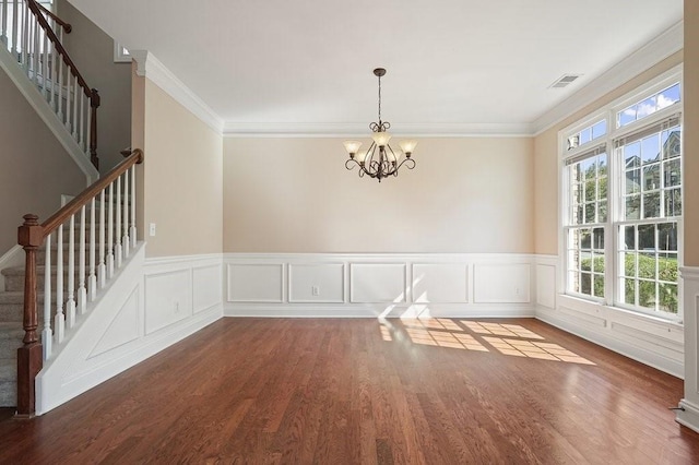 unfurnished dining area featuring ornamental molding, an inviting chandelier, and wood-type flooring