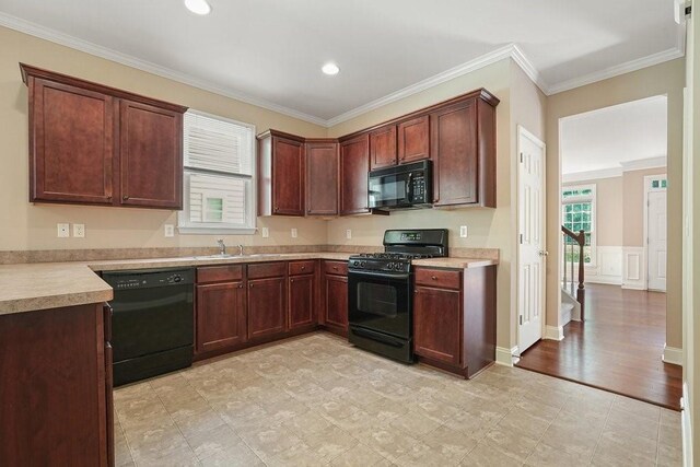 kitchen with crown molding, black appliances, and sink