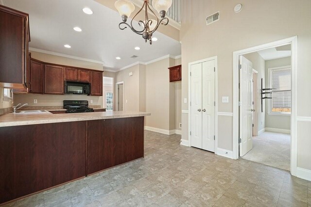 kitchen with black appliances, decorative light fixtures, light carpet, sink, and kitchen peninsula