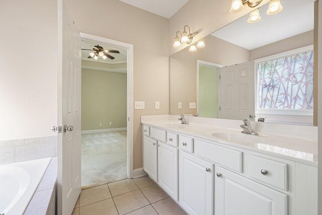 bathroom featuring tile patterned flooring, vanity, ceiling fan, a relaxing tiled tub, and crown molding