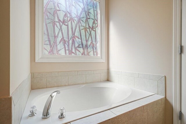 bathroom with plenty of natural light and tiled bath