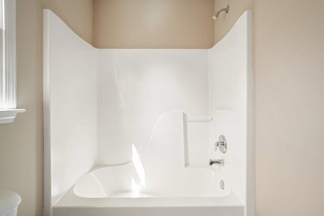 bathroom with bathing tub / shower combination and toilet