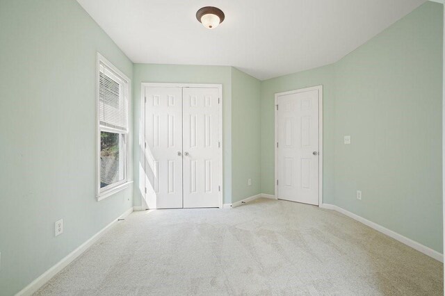 unfurnished bedroom featuring a closet and light carpet