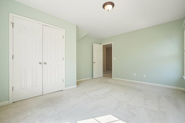 unfurnished bedroom with a closet and light carpet