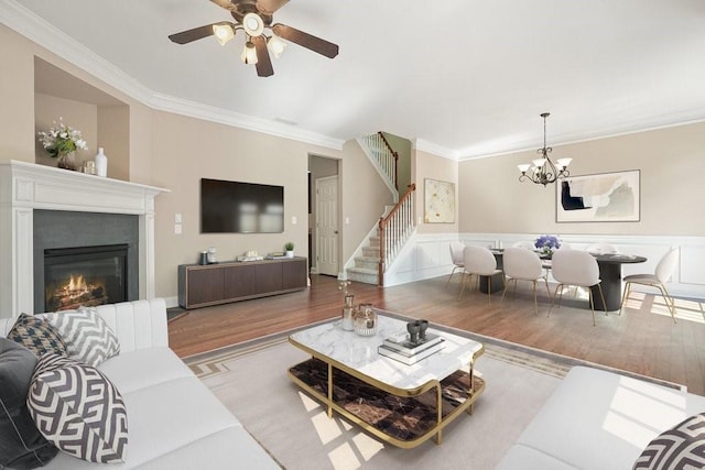 living room with ceiling fan with notable chandelier, ornamental molding, and wood-type flooring