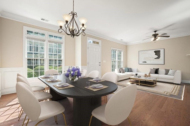 dining area with hardwood / wood-style flooring, ceiling fan with notable chandelier, and crown molding