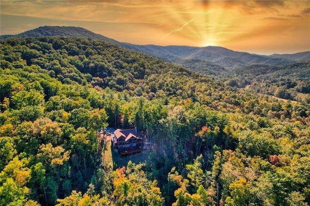 aerial view at dusk featuring a forest view and a mountain view