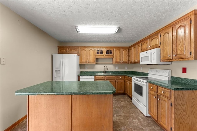 kitchen with a sink, a kitchen island, dark countertops, white appliances, and brown cabinetry