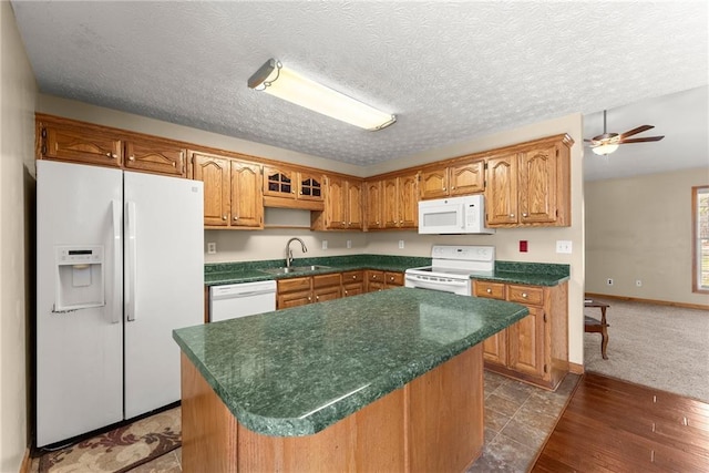 kitchen with a ceiling fan, a sink, dark countertops, a center island, and white appliances