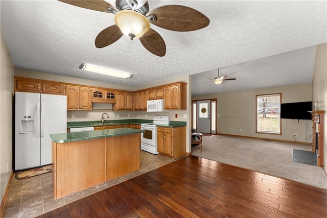 kitchen with a sink, a center island, ceiling fan, white appliances, and dark wood-style flooring