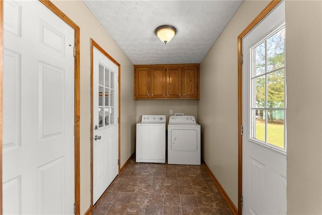 laundry area with baseboards, cabinet space, a textured ceiling, and washing machine and dryer