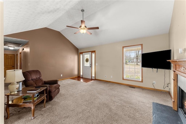 living area featuring a fireplace with flush hearth, a ceiling fan, carpet flooring, baseboards, and vaulted ceiling