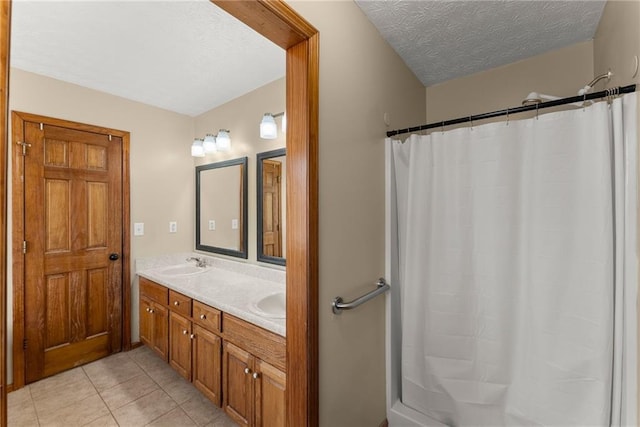 full bathroom featuring a shower with shower curtain, double vanity, a sink, tile patterned flooring, and a textured ceiling