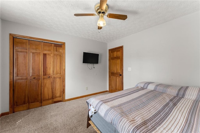 carpeted bedroom featuring a closet, baseboards, a textured ceiling, and ceiling fan