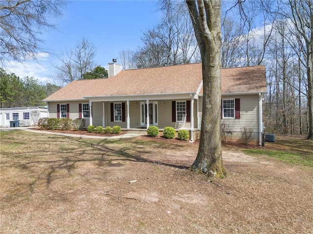 single story home with a shingled roof, a porch, central AC, and a chimney