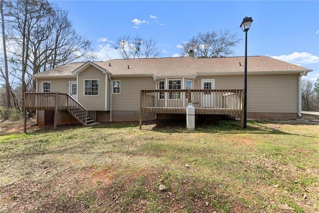 rear view of property with a deck, stairway, a lawn, and roof with shingles