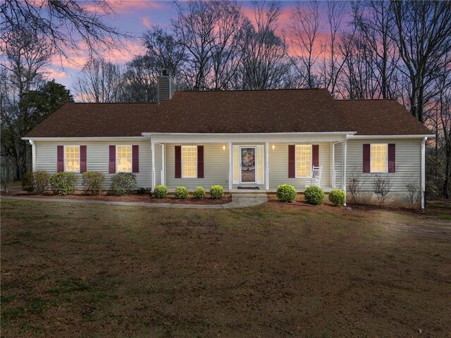 ranch-style home featuring a lawn and a chimney