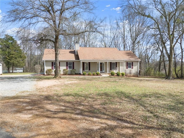 ranch-style home with a front yard, covered porch, and a chimney