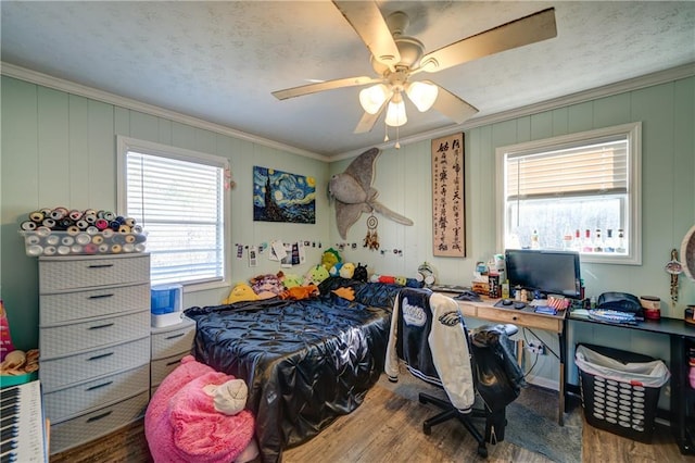 bedroom featuring a textured ceiling, ornamental molding, wood finished floors, and a ceiling fan