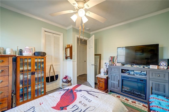 bedroom featuring ornamental molding, a closet, wainscoting, and ceiling fan