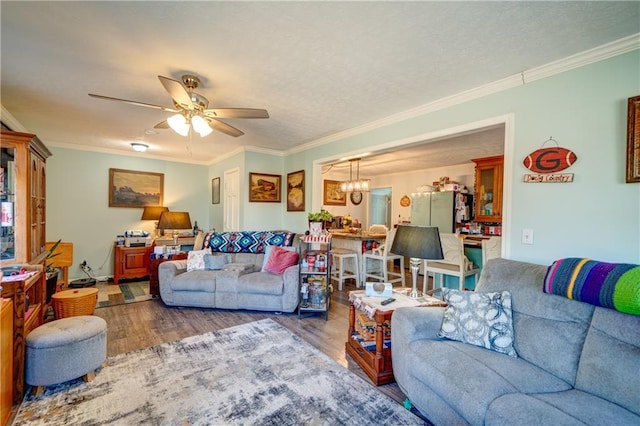 living room with ceiling fan with notable chandelier, ornamental molding, a textured ceiling, and wood finished floors