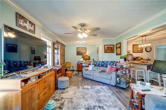 living area featuring crown molding, wood finished floors, and ceiling fan with notable chandelier