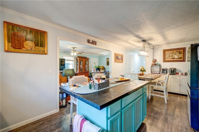 kitchen featuring dark wood-style floors, blue cabinetry, wooden counters, and freestanding refrigerator